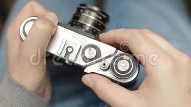 一位年轻的摄影师改变老式老电影相机的快门速度，聚焦并拍照。 特写镜头。
